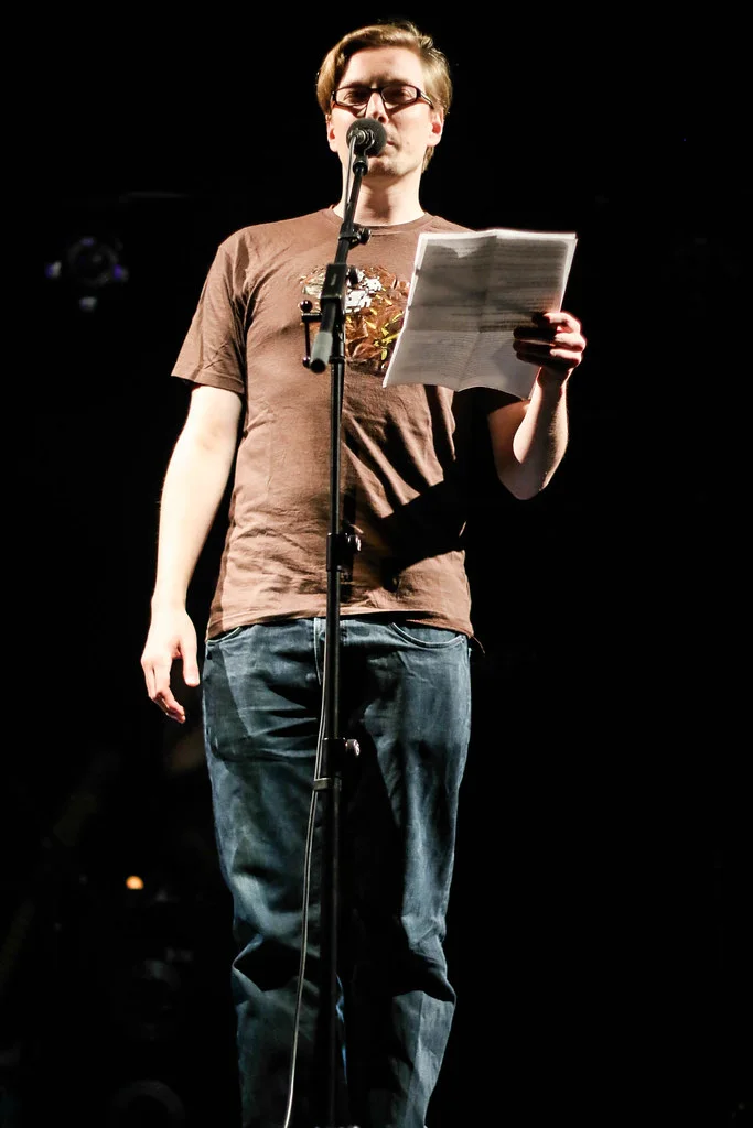 Tom Schildhauer performing at a Poetry Slam, reading at the microphone